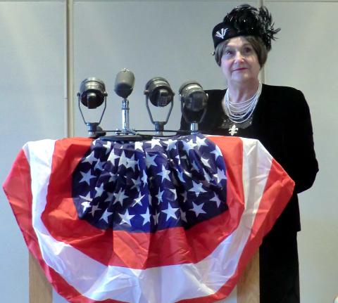 red, white and blue bunting on a podium with microphones. Woman behind the podium