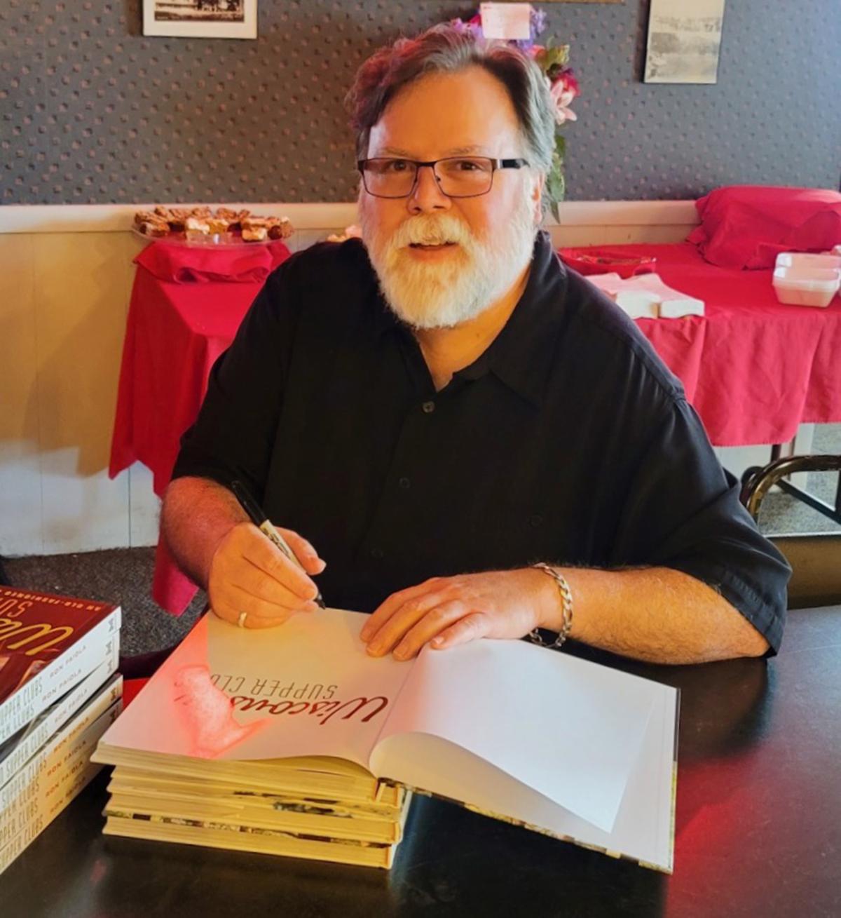 Photograph of Ron Faiola writing in a book